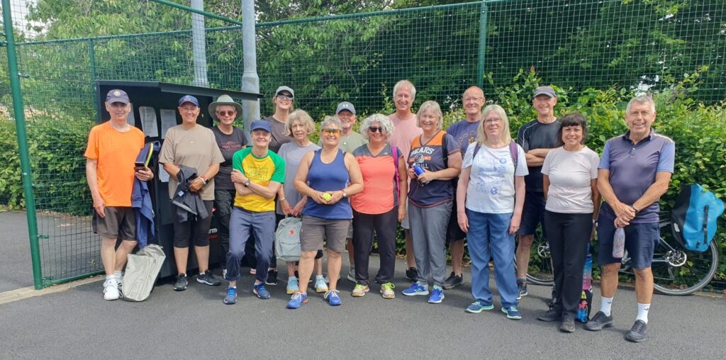 A group of people holding pickleball bats on a park court